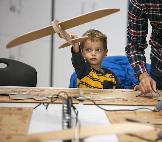 Kindergarten aged male student with airplane model at STEM night